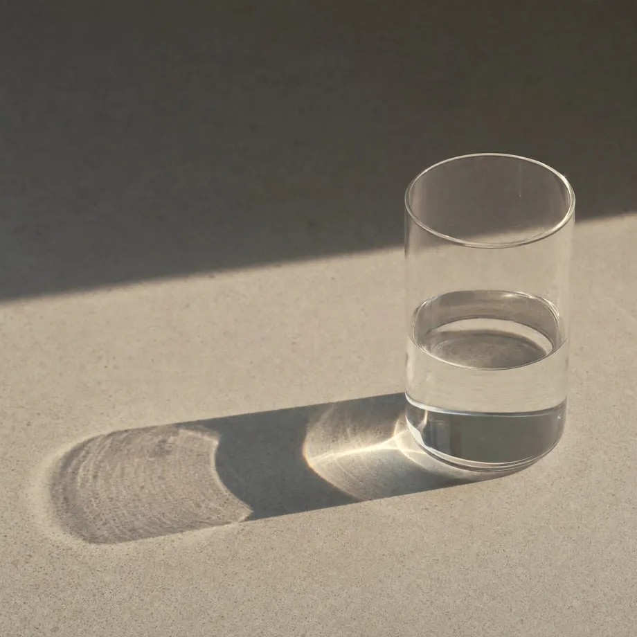 A single clear glass of water catching light on a plain surface.