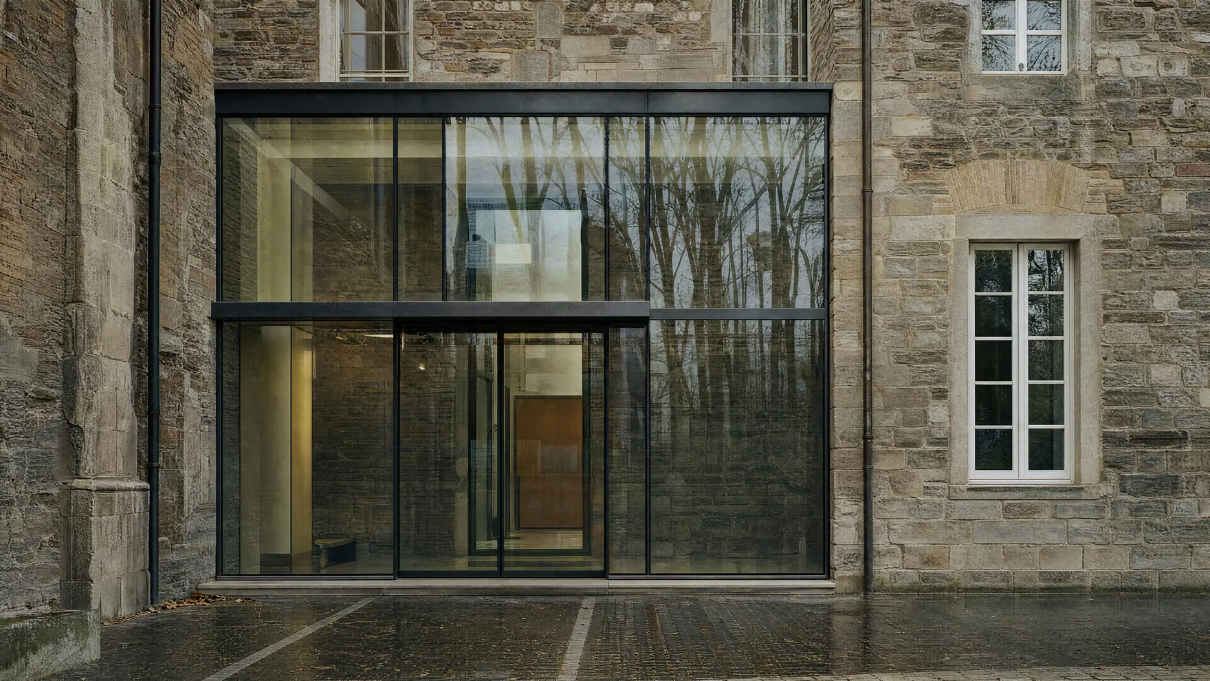 A new glass entrance added onto the front of an older brick building.