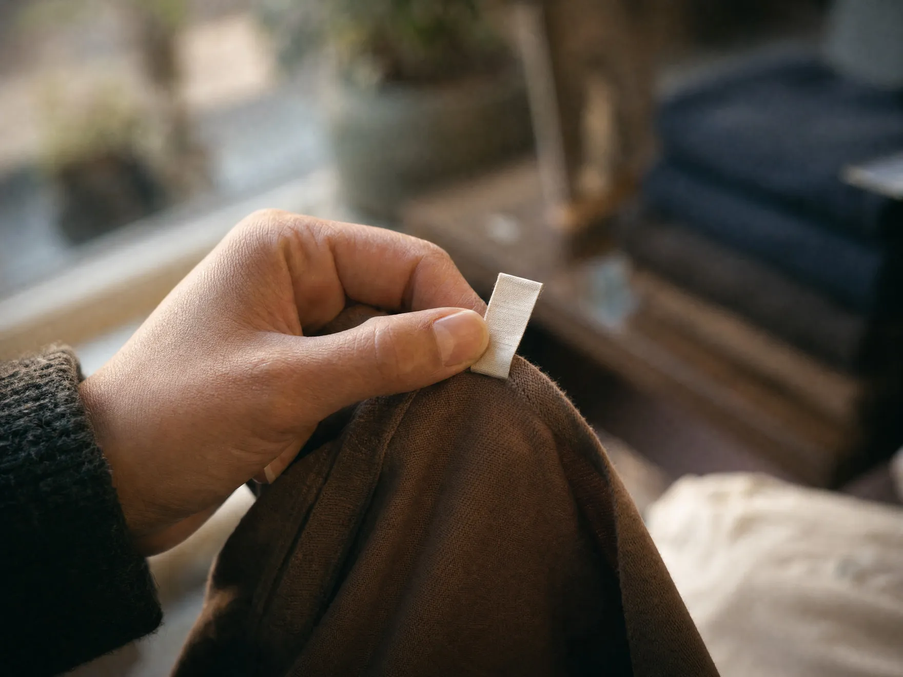 A shopper's hand holding a garment's size tag up to the light.